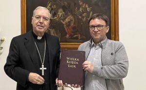 Ks. abp Tommaso Caputo i Marek Woś trzymają Wielką Księgę Łask